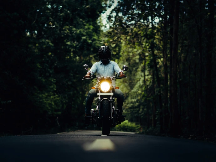 a man riding a motorcycle down a forest road